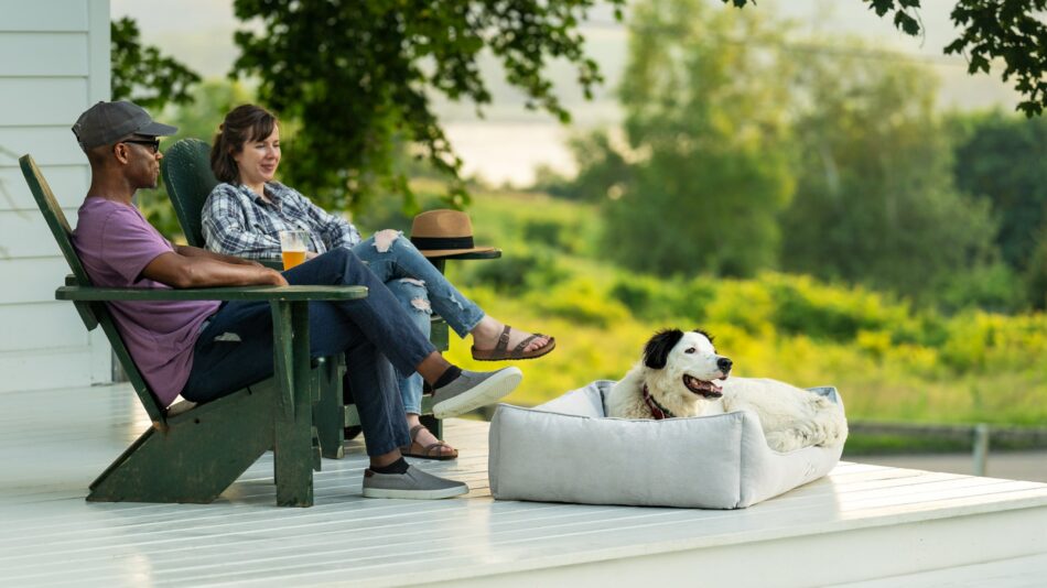 Coppia seduta fuori con il loro cane nella cuccia Nido di Omlet
