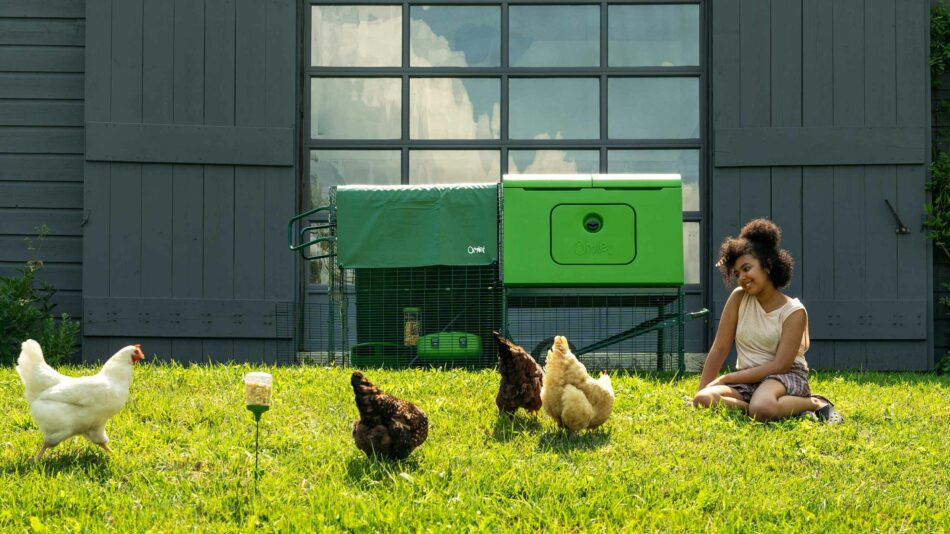Girl sat with free range chickens outside of the Eglu Cube