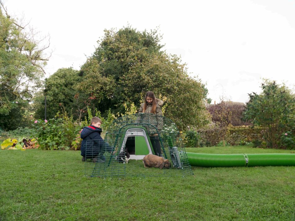 Children outside in winter with their rabbits in their Omlet Eglu Go Rabbit Hutch