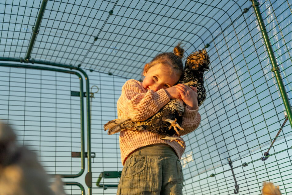 girl cuddling chicken in eglu pro chicken run
