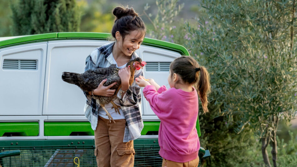 Two girls with a chicken by the Eglu Pro