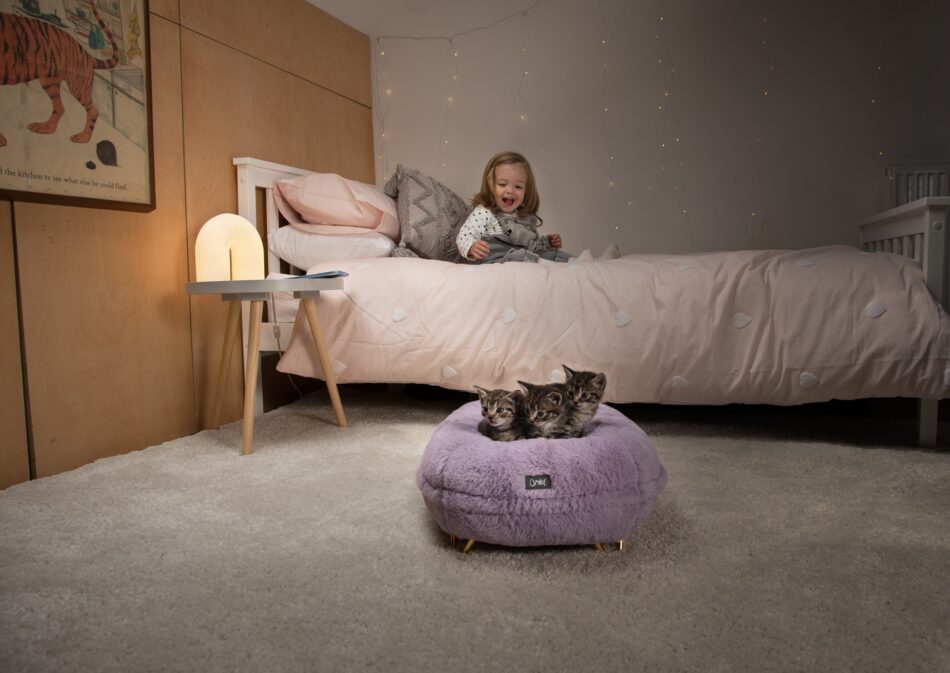 Meisje in bed kijkend kittens in Maya Donut kattenmand in de kleur poederlila