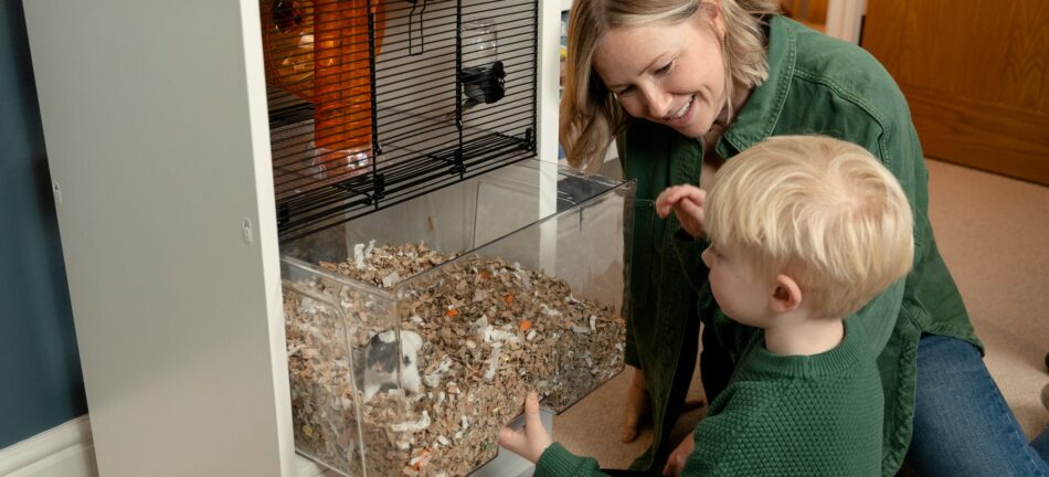 Jongen speelt met hamster in Omlet Qute hamsterkooi samen met zijn moeder