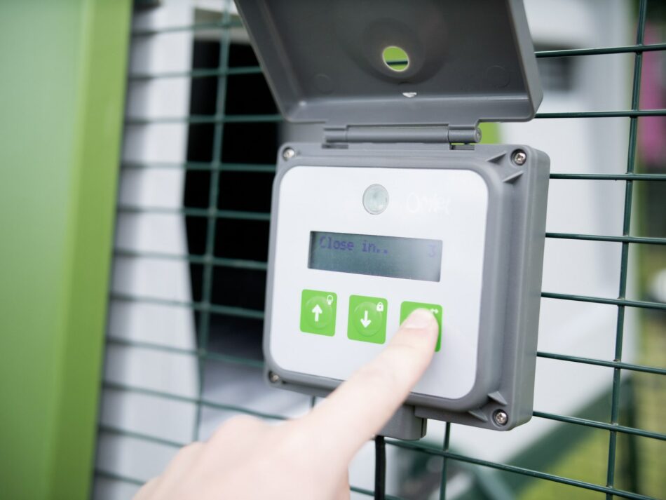 Chicken keeper pressing on the controls of the Omlet Automatic Chicken Coop Door