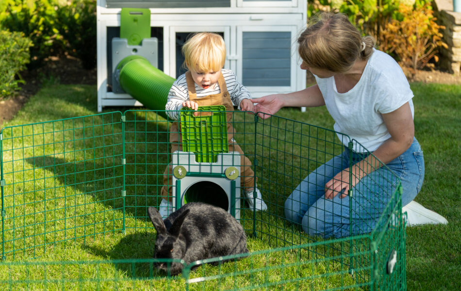 Barn og kvinde leger med kanin i Omlet Zippi-legegård