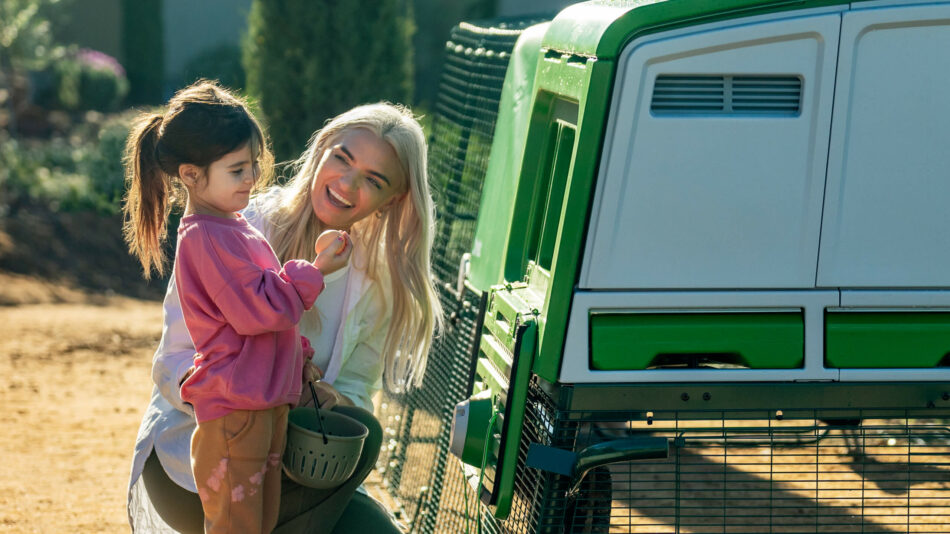 Girl and woman looking at eggs next to the Eglu Pro chicken coop