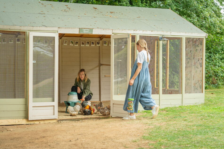 girl walking towards wooden chicken run with open doors