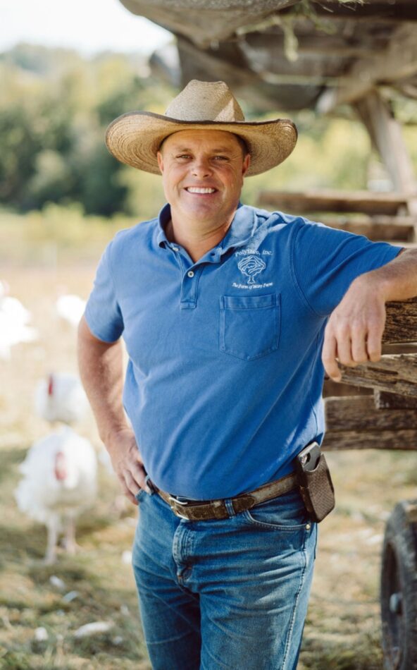Daniel Salatin smiling in straw hat and blue polo top
