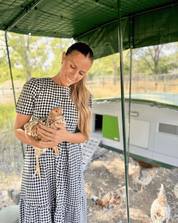 Lyndsey holding her chicken, stood in her walk in run